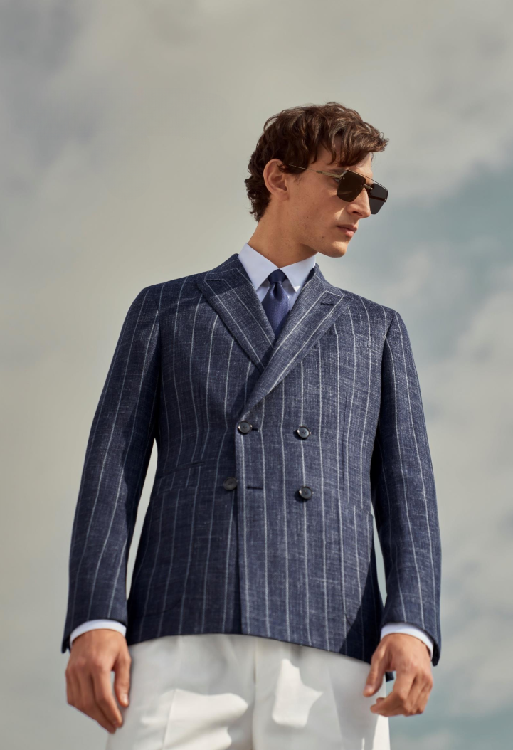 Male model wearing white Zegna pants and blue Zegna jacket with white stripes