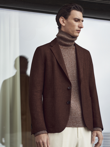 Model wearing burgundy suit with maroon turtleneck and white pants all made by Zegna