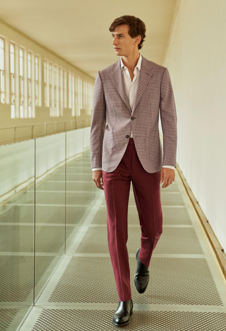 Male model walking and wearing checkered red and white Zegna jacket with maroon Zegna dress pants