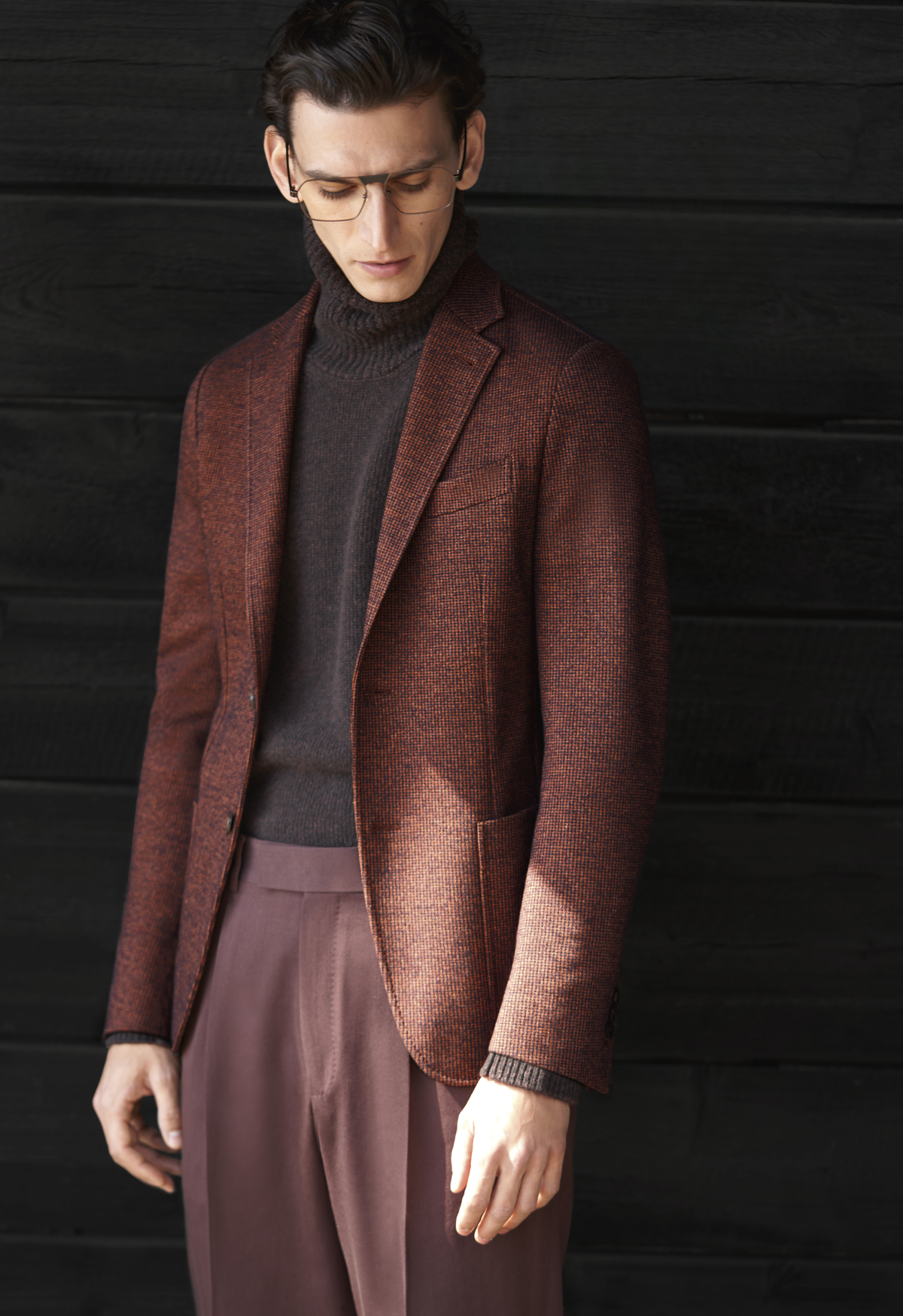 Model wearing maroon jacket with black sweater and light maroon pants all made by Zegna