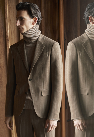 Model in beige suit and turtleneck both by Zegna with a mirror reflection on the right
