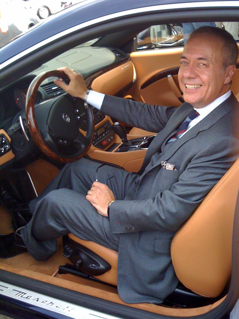 John De Laurentiis sitting in the drivers seat of a Maserati with door open